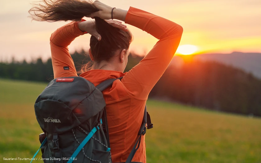 Eine Frau bindet sich einen Zopf bei Sonnenaufgang