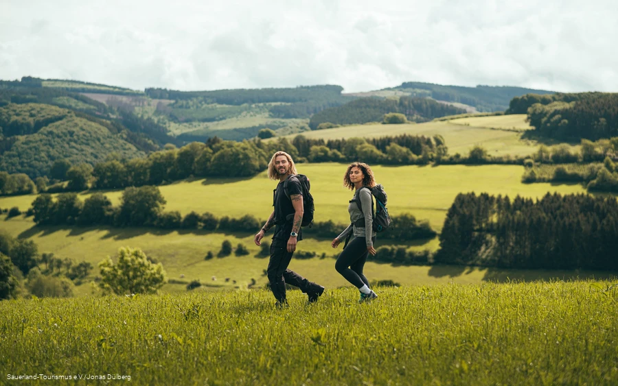 Zwei junge Leute wandern oberhalb von Sundern-Hagen über eine Wiese