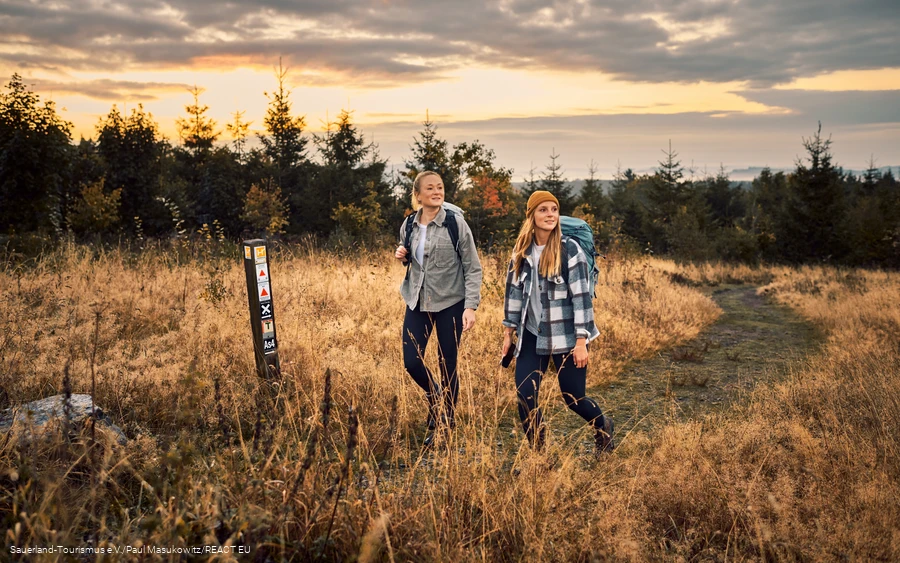 zwei Wanderinnen wandern im Sonnenaufgang auf den Kahlen Asten