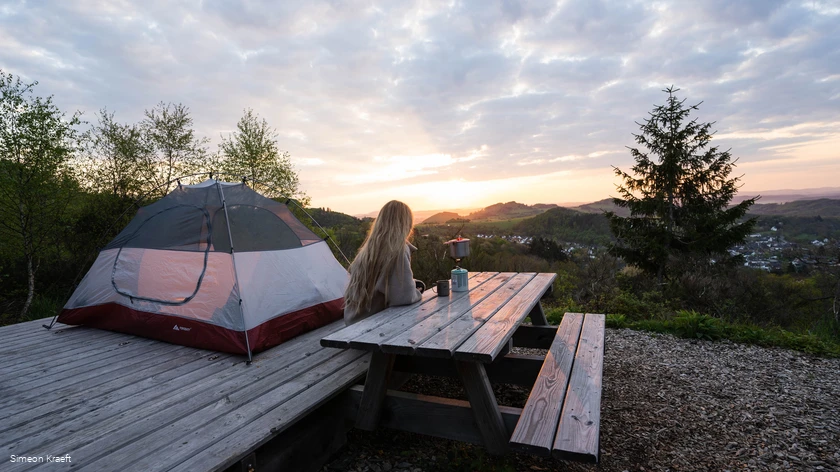 Eine Frau genie&szlig;t den Sonnenaufgang am Trekkingplatz Talblick