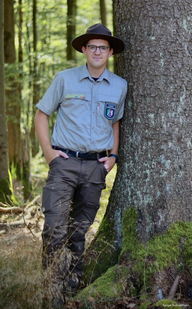 Ranger Torben Adler  neben einem Baum.